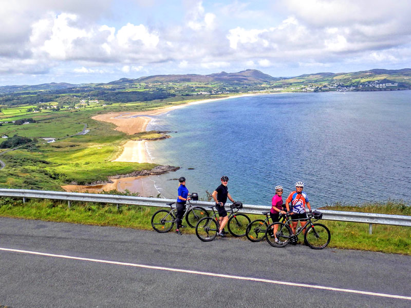 Cyclists group standing at the bottom of a climb on a backdrop of azure blue sea